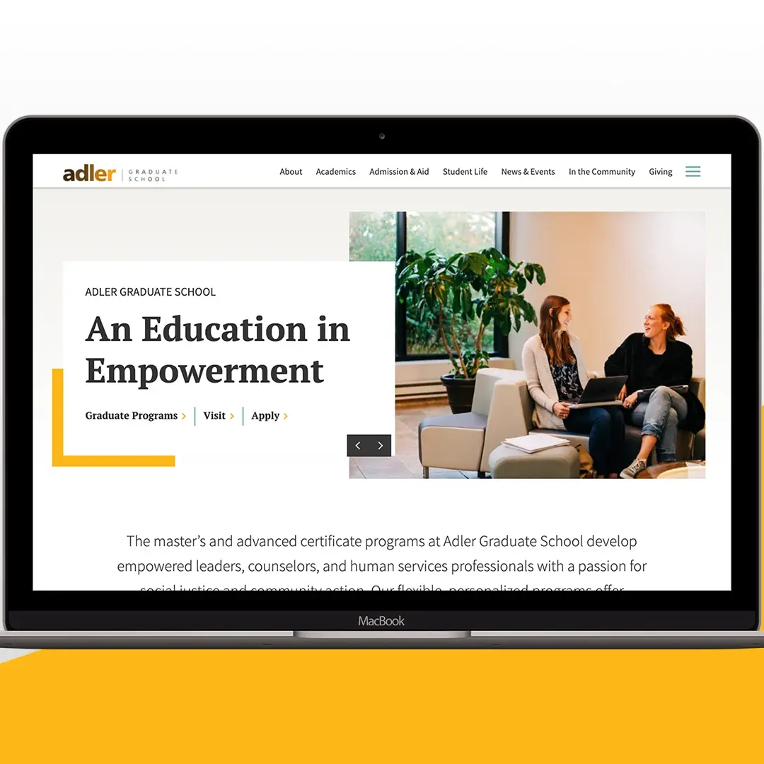 A laptop with the Adler Graduate School website on the screen