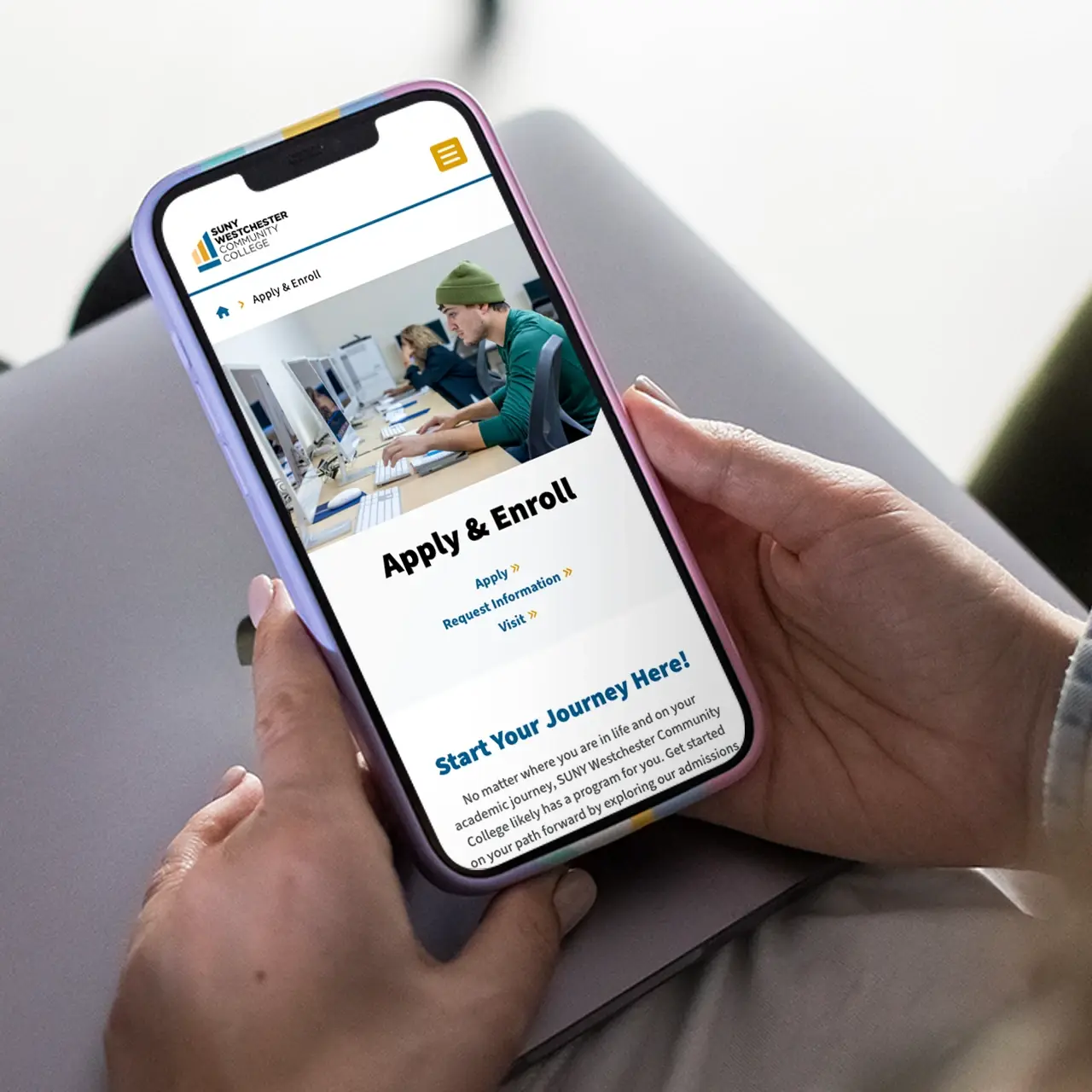 A person holding a smartphone with the Apply and Enroll page of the SUNY Westchester Community College website on the screen
